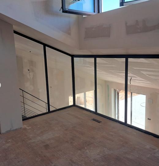 Galería interior acristalada con escalera metálica en reforma residencial, Zaragoza